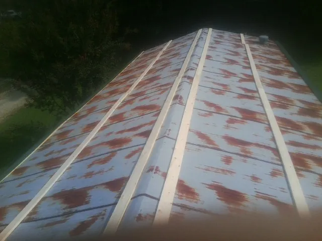 Rusted metal roof panels with new wood purlins before replacement — Storm Damage Roof Repair in North Woodstock by Roofing Brothers