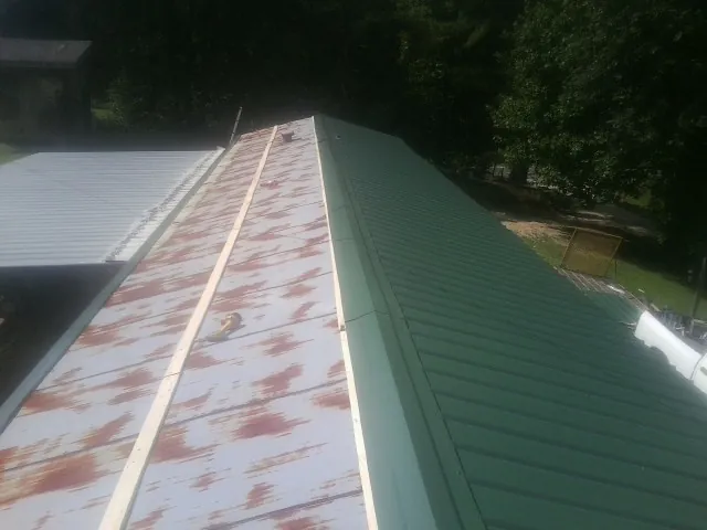 Old rusted panels beside newly installed green metal roofing — Wind Damage Roof Repair by Roofing Brothers in North Woodstock