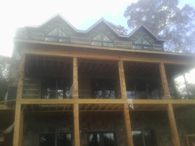 Dormers and porch framing on a large log home under construction — Roof Coating work by our crew in North Woodstock