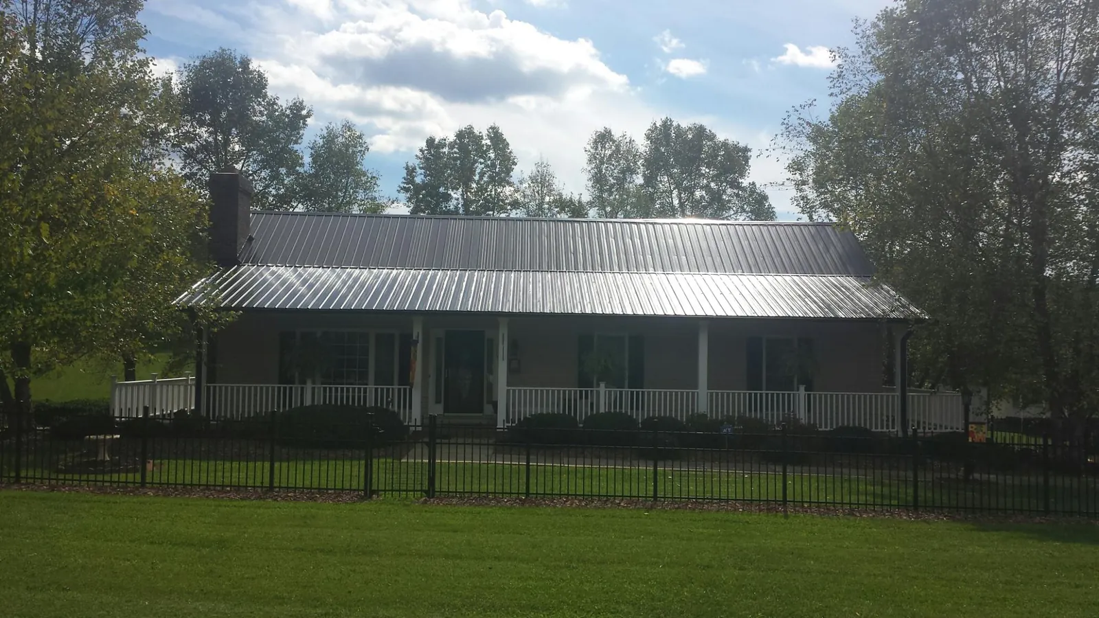 Gray metal roof on a brick ranch with a full width front porch — Gutter Guard Installation work by our crew in North Woodstock