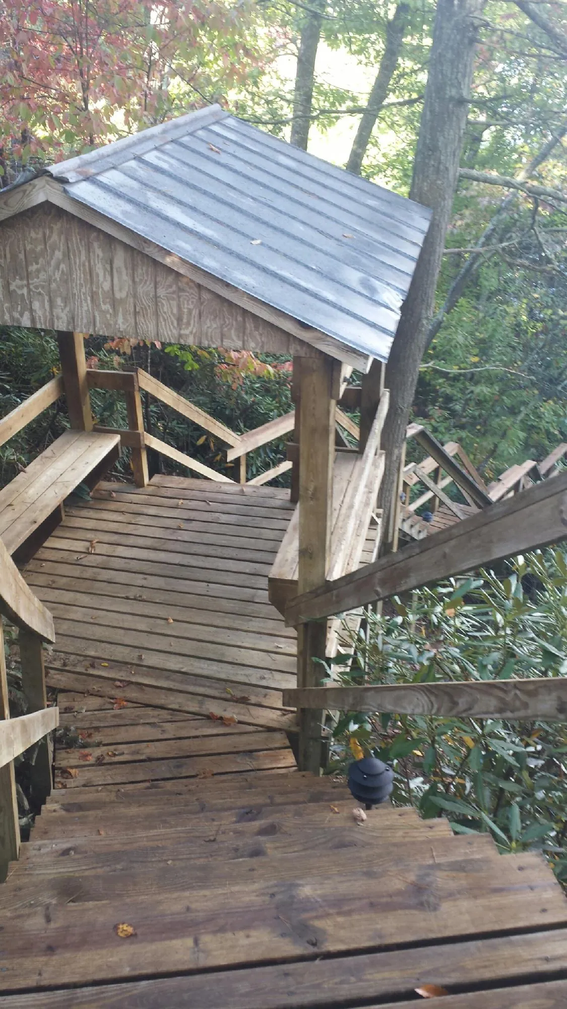 Metal roofed shelter over wooden steps on a wooded walkway — Skylight Repair & Installation work by our crew in North Woodstock