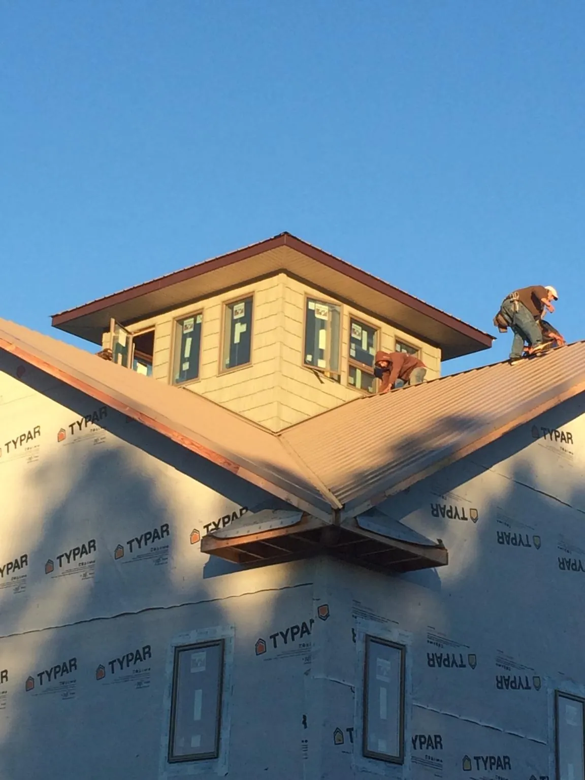 Roofers working around a rooftop cupola on a new metal roof at sunset — Roof Waterproofing in North Woodstock by Roofing Brothers